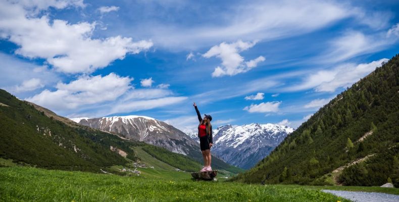 Woman celebrating atop a hill in Livigno, Italy, with stunning mountain views.