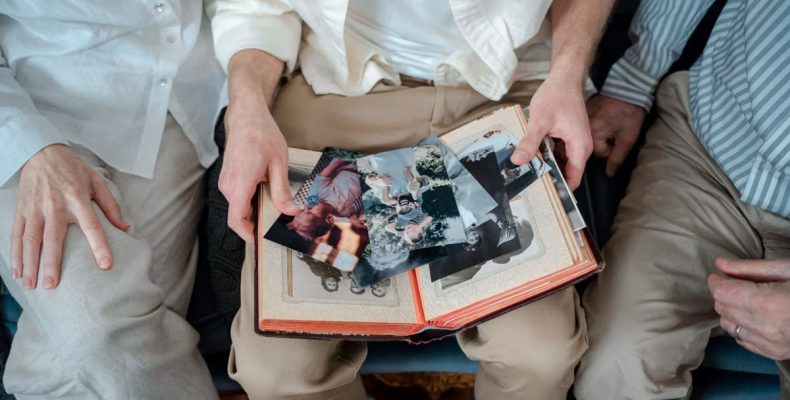 A family of three enjoying old photos together, sharing cherished memories.