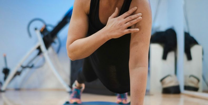 A woman in a black tank top is doing yoga